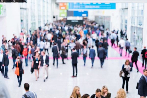Blurry image of bustling participant traffic at a conference.